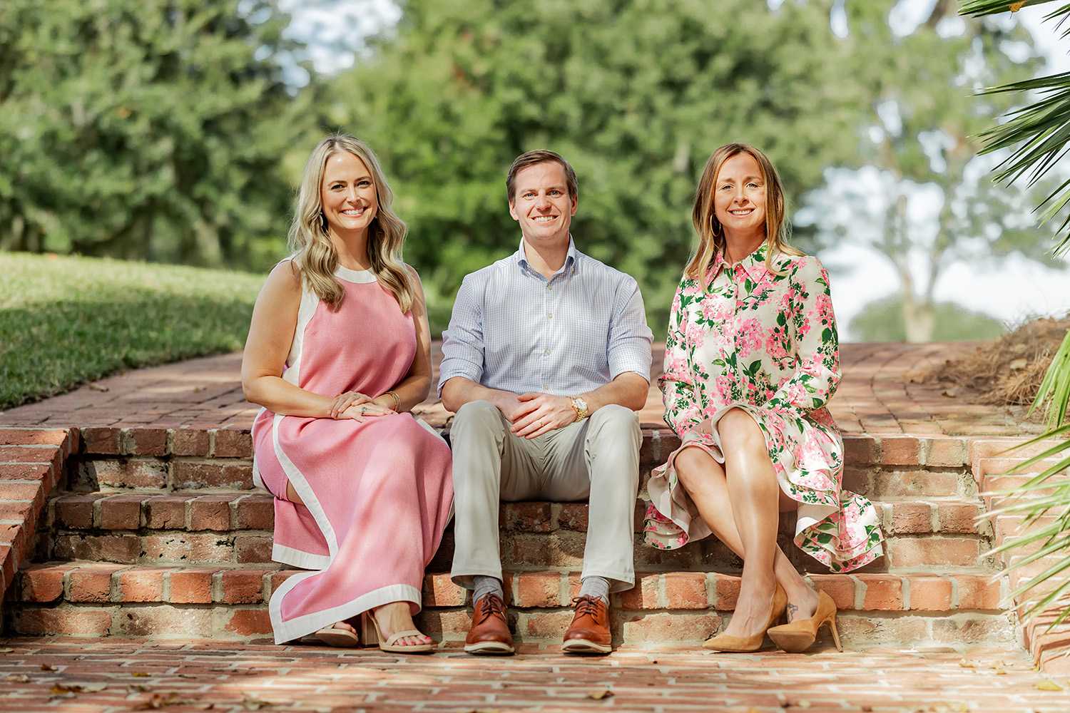 Two people standing on lawn with palm tree behind.